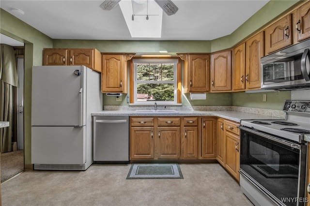 kitchen with ceiling fan, sink, appliances with stainless steel finishes, and a skylight