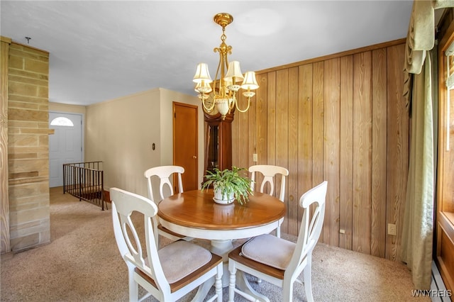 dining space with an inviting chandelier, baseboard heating, light colored carpet, and wooden walls