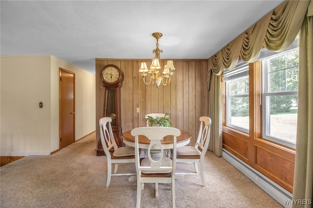 carpeted dining room featuring a baseboard heating unit, a chandelier, and wooden walls