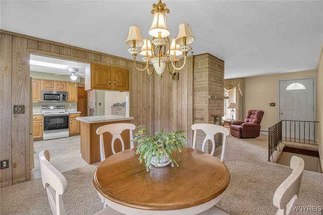 dining space with wood walls, light carpet, and ceiling fan with notable chandelier