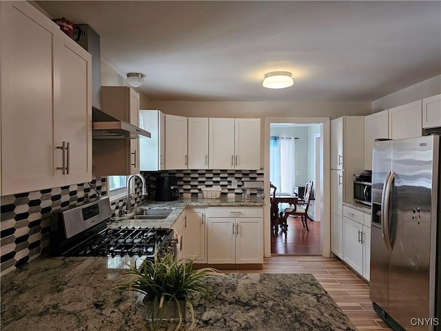 kitchen featuring white cabinetry, appliances with stainless steel finishes, tasteful backsplash, light stone counters, and sink