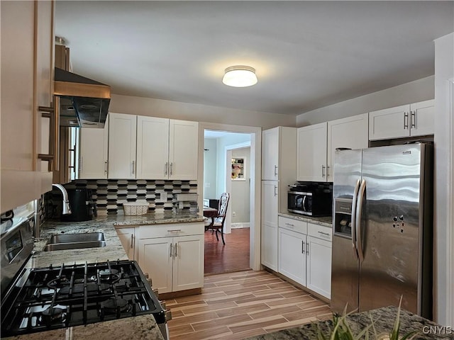 kitchen with stainless steel appliances, light hardwood / wood-style flooring, white cabinetry, and tasteful backsplash