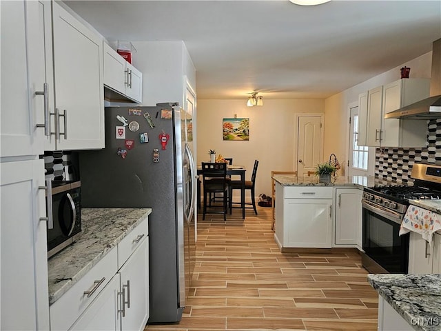 kitchen with white cabinetry, appliances with stainless steel finishes, backsplash, light stone countertops, and wall chimney exhaust hood