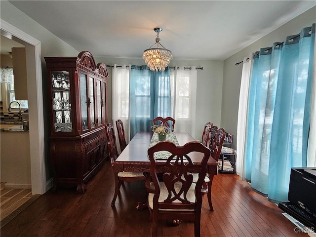 dining room with dark wood-type flooring, an inviting chandelier, and sink