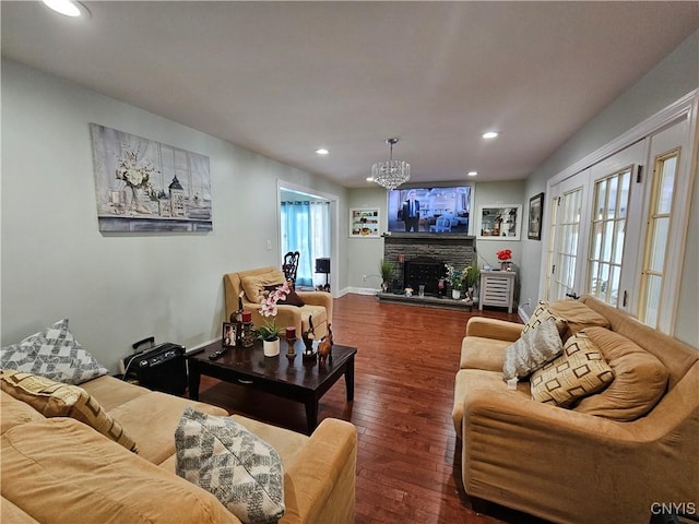 living room with a fireplace, dark hardwood / wood-style flooring, and a chandelier