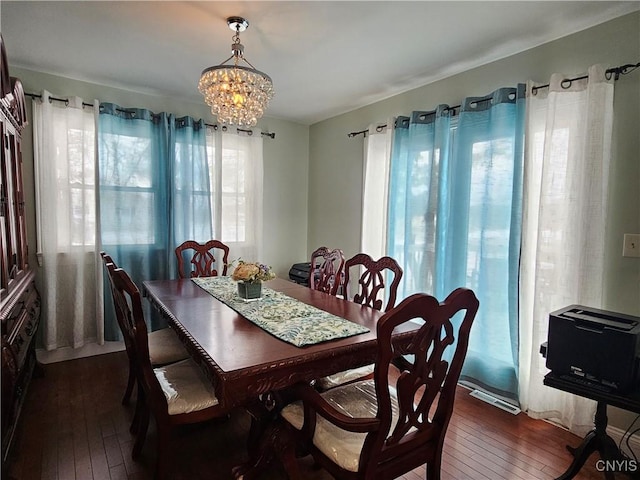 dining space with dark hardwood / wood-style floors and a chandelier