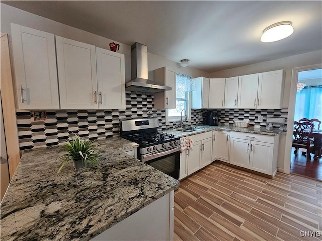 kitchen with white cabinets, wall chimney exhaust hood, sink, stainless steel range with gas cooktop, and stone counters