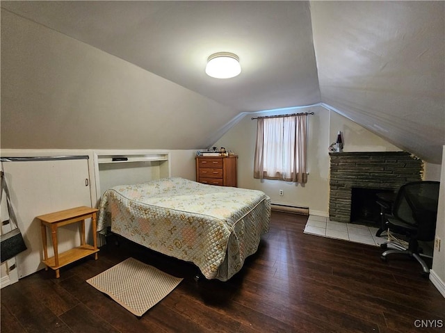 bedroom featuring a baseboard heating unit, lofted ceiling, dark hardwood / wood-style floors, and a stone fireplace