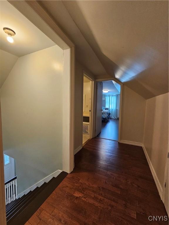 corridor with dark hardwood / wood-style floors and lofted ceiling