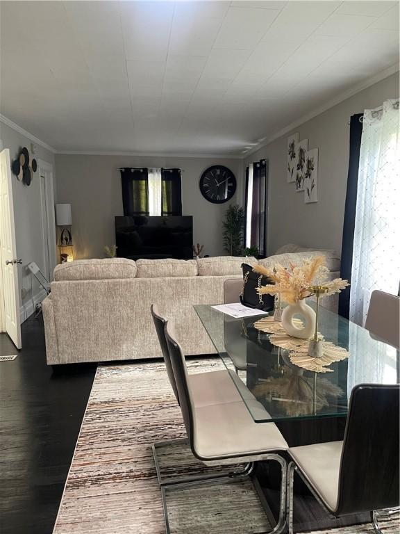 dining area featuring wood-type flooring and crown molding