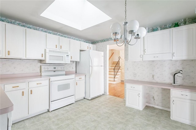 kitchen featuring white cabinetry, a chandelier, hanging light fixtures, and white appliances