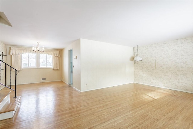 spare room featuring an inviting chandelier and light hardwood / wood-style flooring