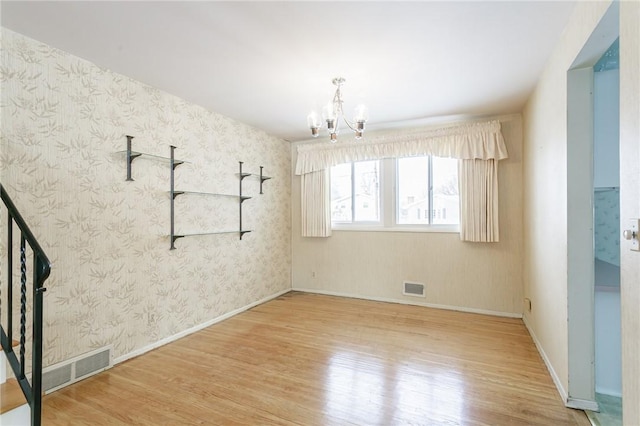 spare room featuring wood-type flooring and an inviting chandelier