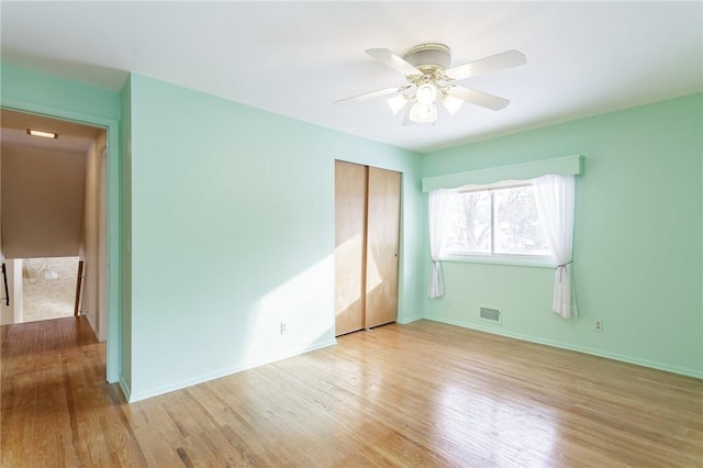 unfurnished bedroom featuring ceiling fan, a closet, and light hardwood / wood-style flooring