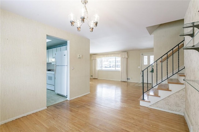 foyer entrance with light hardwood / wood-style flooring and a chandelier