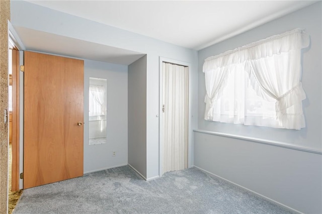 unfurnished bedroom featuring light carpet, a closet, and multiple windows