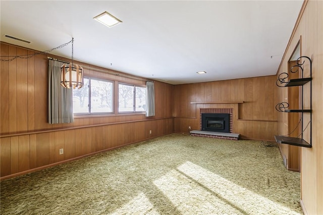 unfurnished living room with a fireplace, wooden walls, and carpet flooring