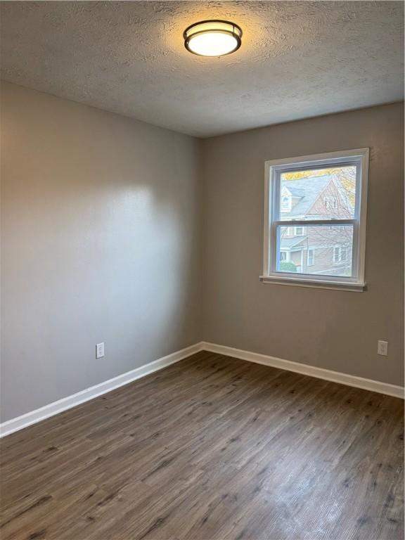 spare room featuring dark wood-type flooring and a textured ceiling