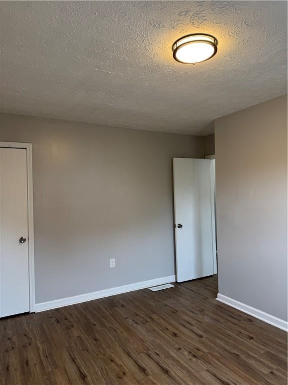 spare room featuring dark wood-type flooring and a textured ceiling