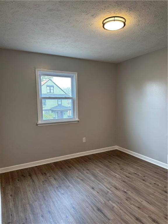 spare room featuring a textured ceiling and dark wood-type flooring