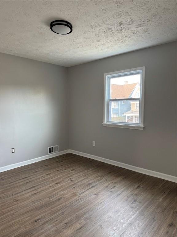 spare room featuring dark hardwood / wood-style flooring and a textured ceiling