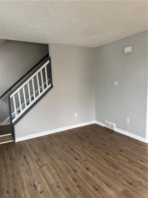 interior space with a textured ceiling and dark hardwood / wood-style flooring