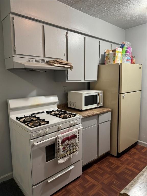 kitchen with white appliances, white cabinets, a textured ceiling, and dark parquet floors