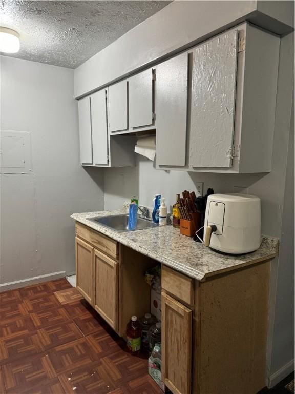 kitchen with a textured ceiling, white cabinetry, dark parquet floors, and sink