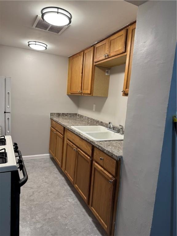 kitchen with sink, white fridge, and gas stove