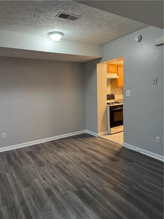 unfurnished living room with dark wood-type flooring and a textured ceiling