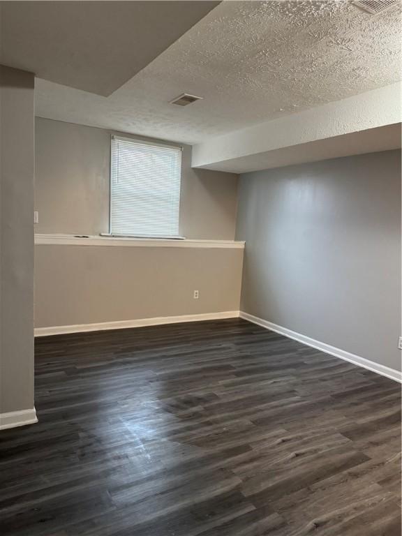 basement featuring a textured ceiling and dark wood-type flooring