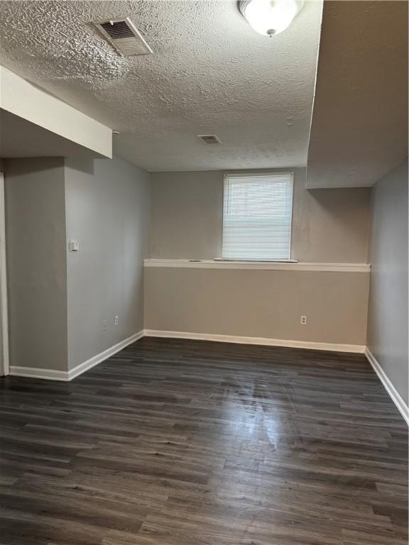 basement featuring a textured ceiling and dark hardwood / wood-style floors