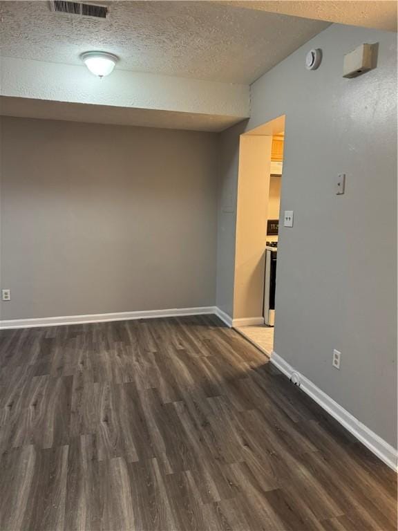 spare room with dark hardwood / wood-style floors and a textured ceiling