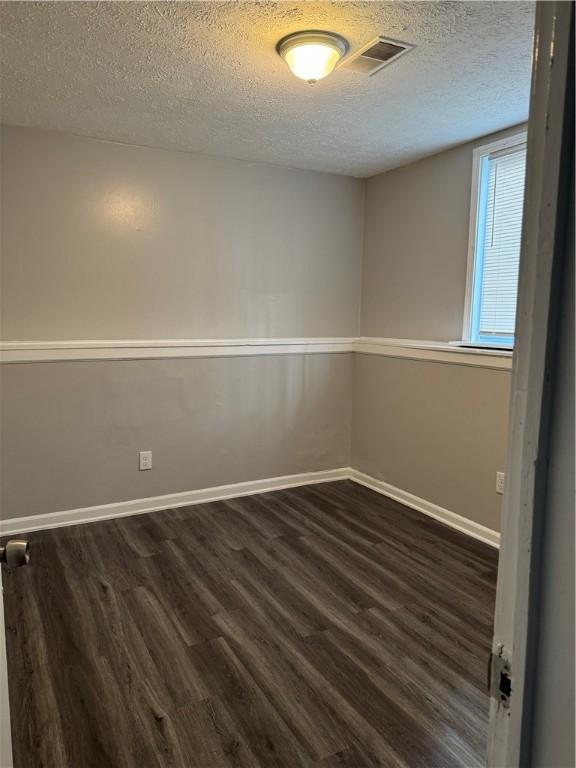 unfurnished room with dark wood-type flooring and a textured ceiling