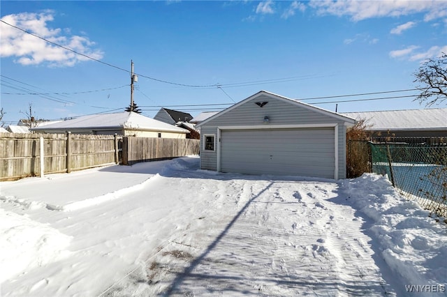 yard layered in snow featuring a garage and an outbuilding