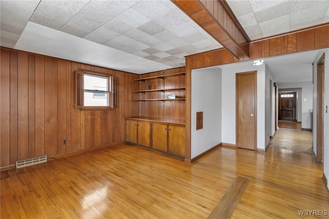 spare room featuring light hardwood / wood-style flooring and wooden walls