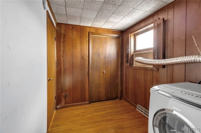 laundry area featuring washer / dryer, wood walls, and light wood-type flooring