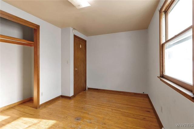 unfurnished bedroom featuring multiple windows, a closet, and light wood-type flooring