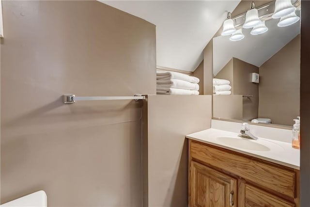 bathroom featuring toilet, vanity, and vaulted ceiling