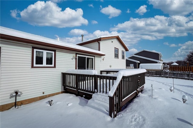 snow covered back of property with a wooden deck