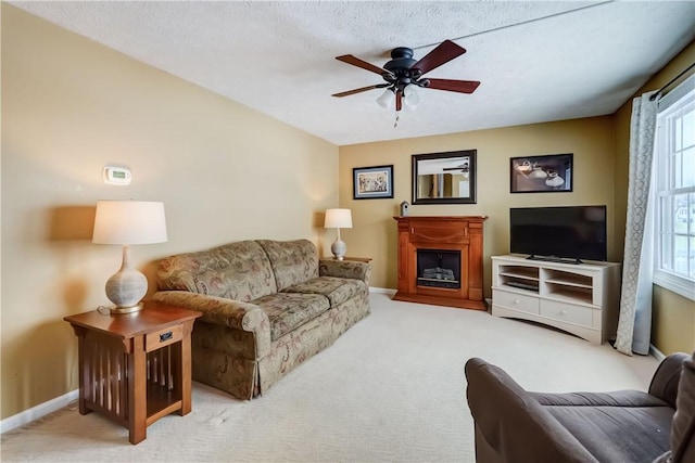 living room with ceiling fan, light colored carpet, a wealth of natural light, and a textured ceiling