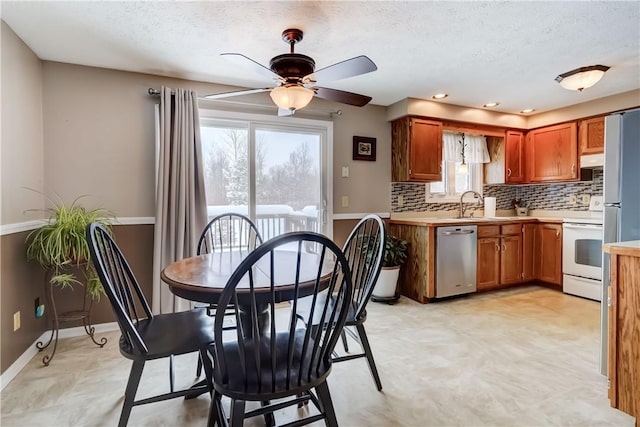 kitchen with white stove, ceiling fan, decorative backsplash, dishwasher, and sink