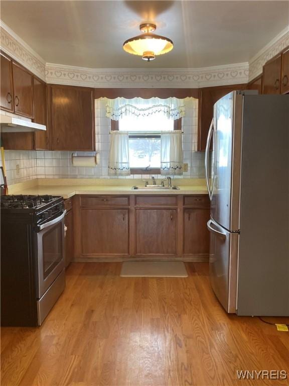 kitchen with light hardwood / wood-style floors, stainless steel appliances, backsplash, ornamental molding, and sink