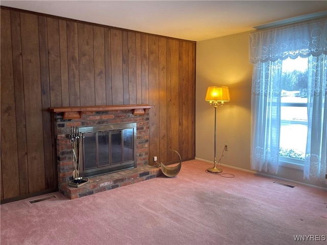 unfurnished living room featuring carpet floors, a brick fireplace, and wooden walls