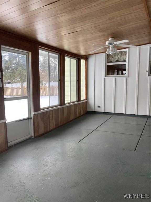 unfurnished sunroom featuring ceiling fan, wood ceiling, and plenty of natural light