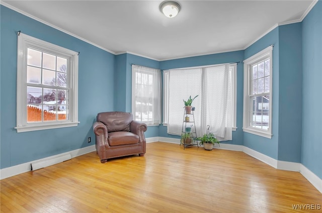 living area with ornamental molding and light hardwood / wood-style flooring