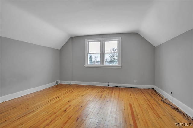 additional living space with light hardwood / wood-style floors and lofted ceiling