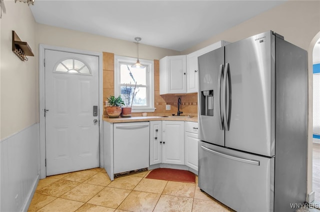 kitchen with stainless steel fridge, sink, white dishwasher, and white cabinetry