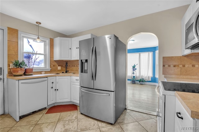 kitchen featuring decorative light fixtures, sink, white cabinetry, and stainless steel appliances