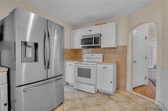 kitchen with backsplash, light tile patterned floors, white cabinetry, and appliances with stainless steel finishes